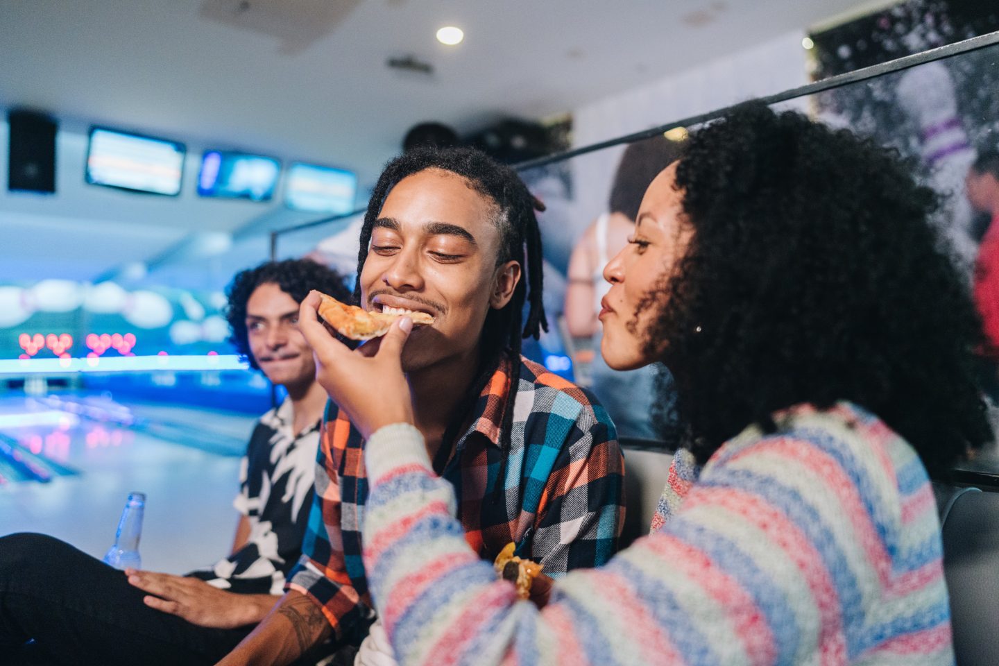 Young woman giving pizza to her friend at a bowling club