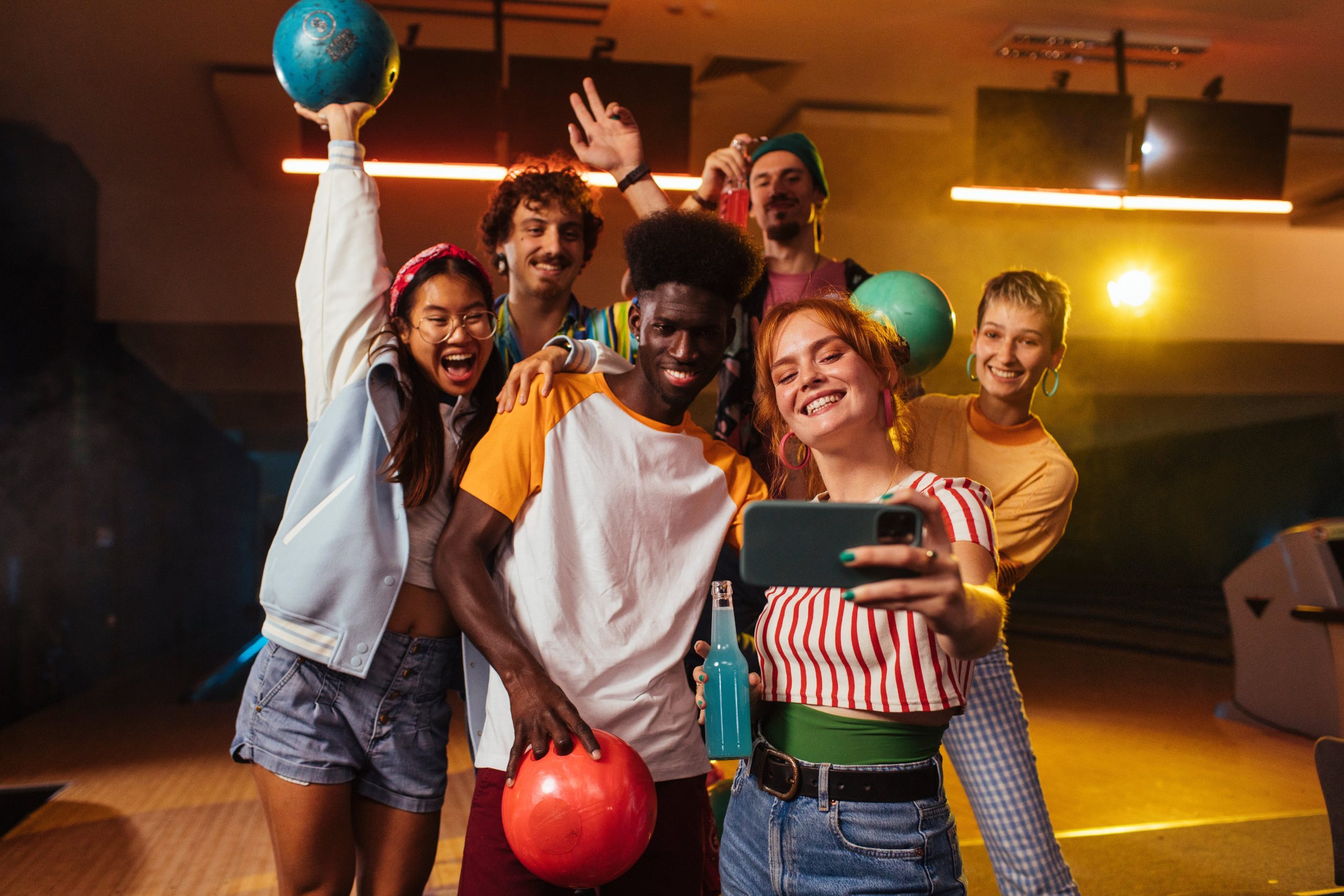 Close friends of all races smile and take a photo before going bowling